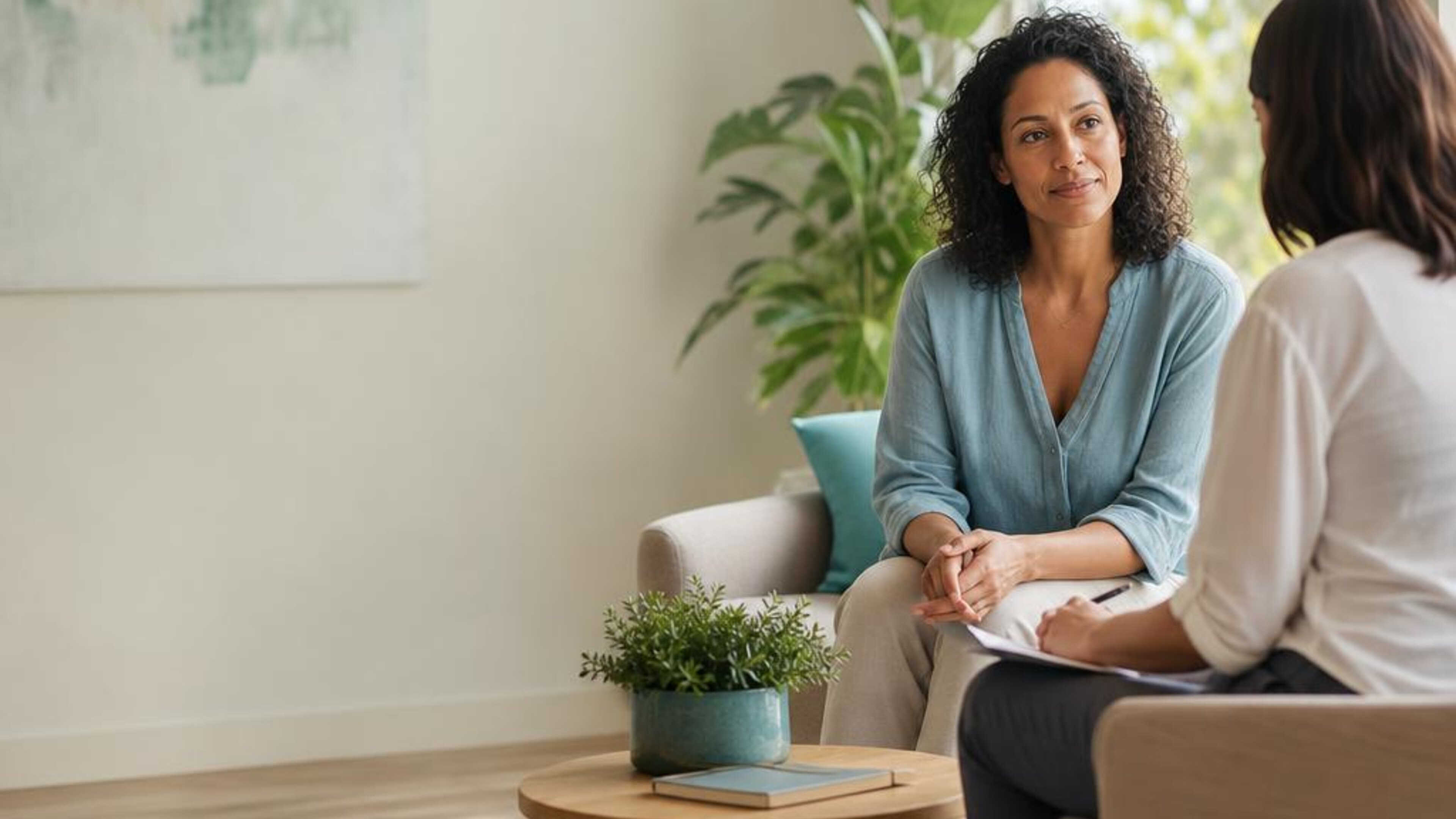 An adult having a supportive conversation with a counselor in a sunlit room, illustrating addiction support. Generated illustration, not actual patients or clinic staff.